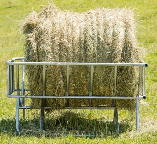A cradle style bale feeder with a large round bale in pasture.