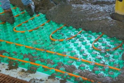 workers covering insulated floor panels with cement