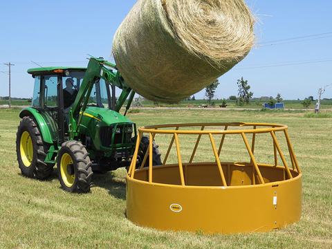 cattle hay feeder being loaded in a pasture