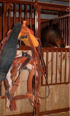 saddle rack in horse barn alleyway with two saddle on it