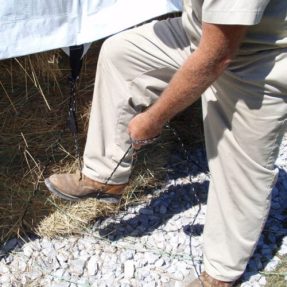 rancher tightening a hay tarp tie down cinch