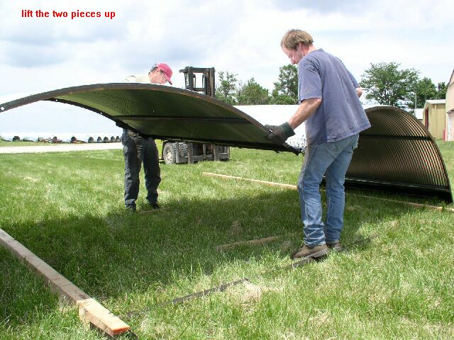two men lifting the center section of the animal shelter