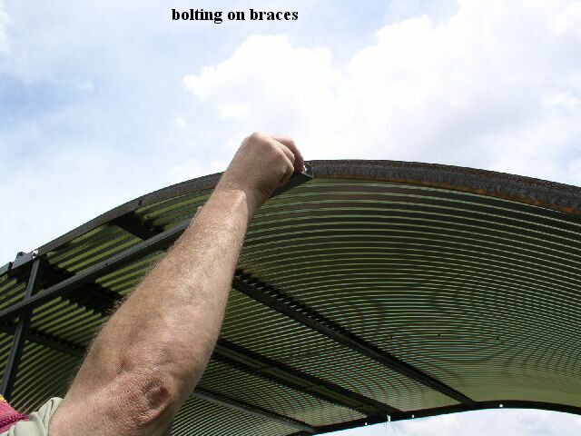a man connecting the roof supports on a metal animal shelter