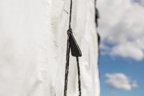 a hay tarp cinch holding down a white hay tarp