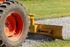 Tractor using grader blade in reverse position