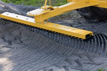 Tractor rake smoothing dirt on farmland